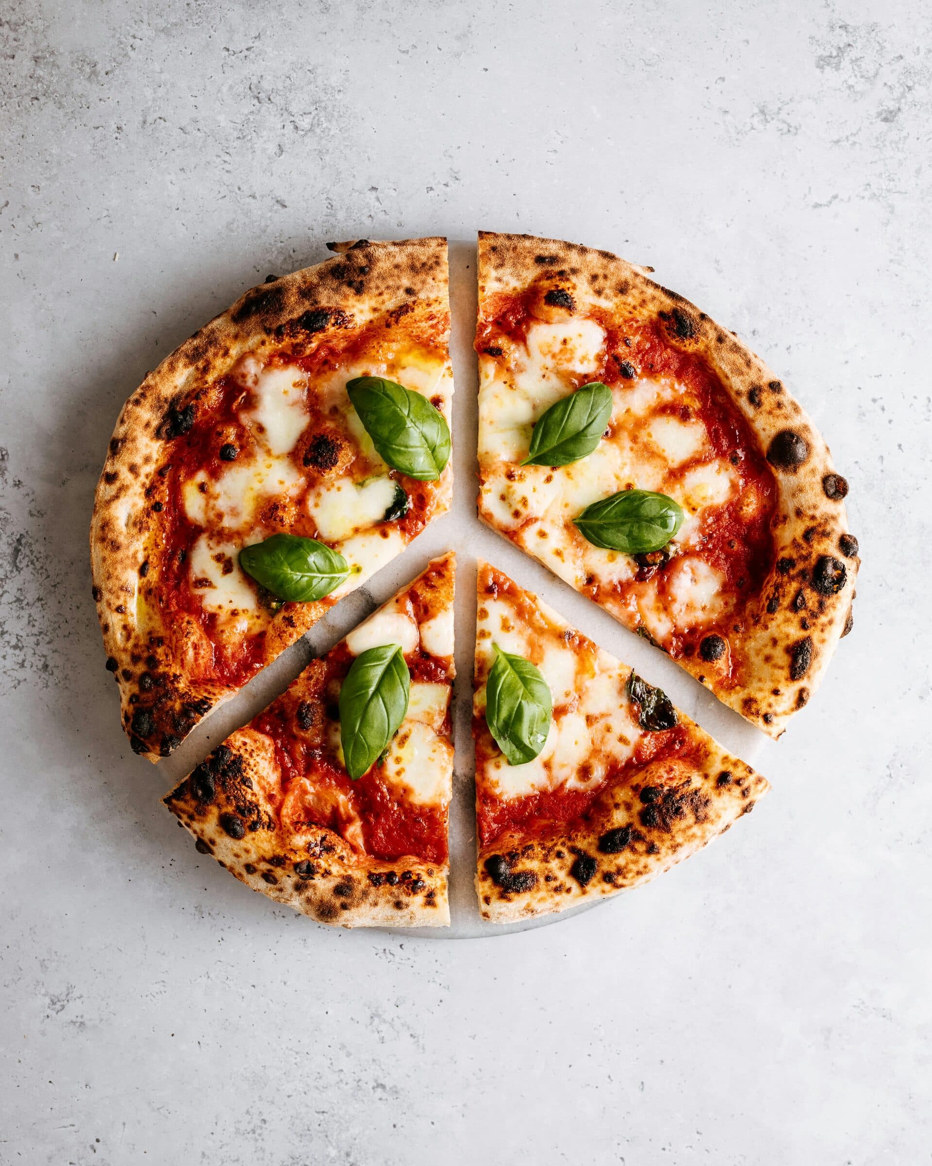 Une pizza margherita sortie du four, coupée en parts